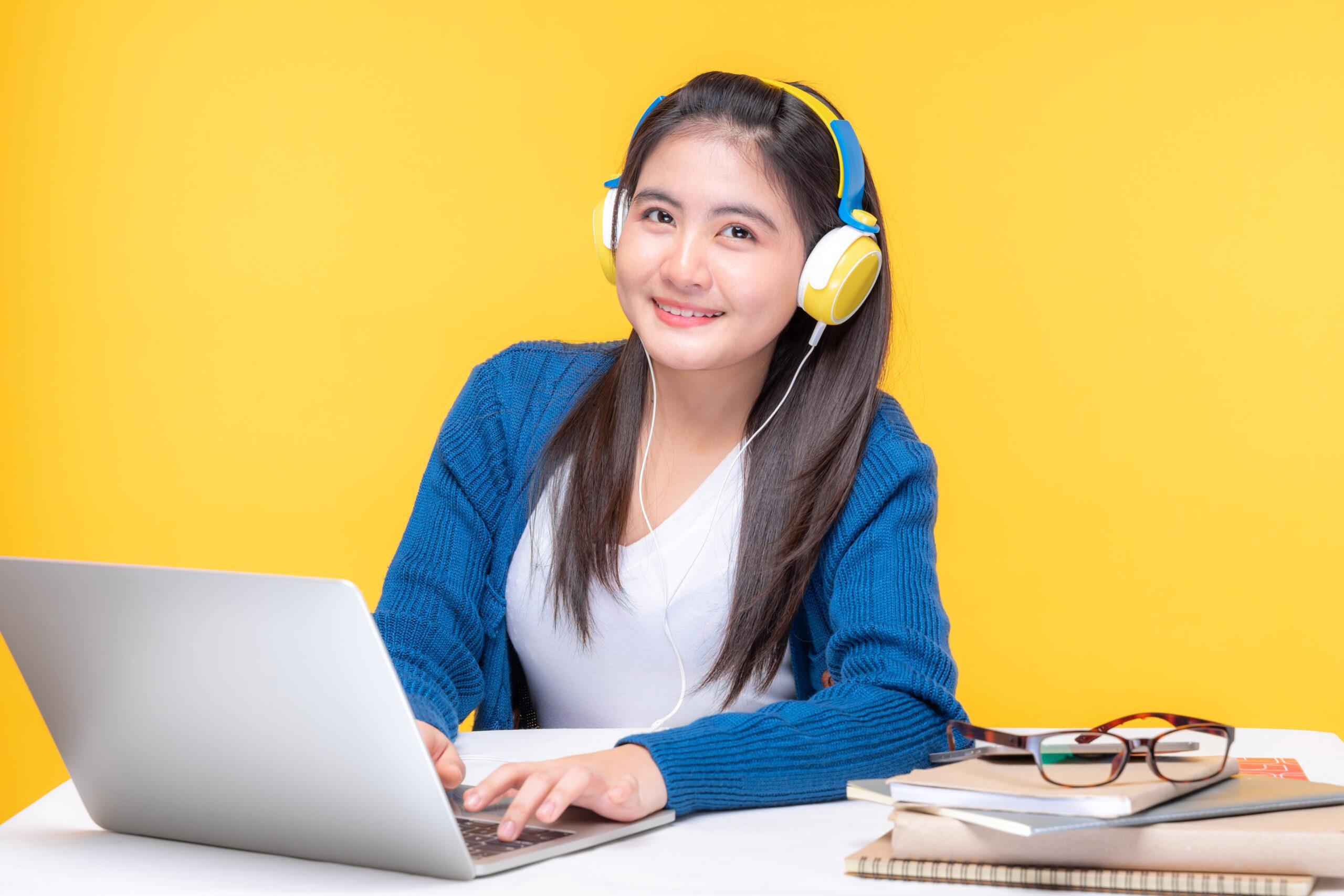 Portrait of a young woman studying at the table with laptop computer and notebook at home - studying online e-learning system