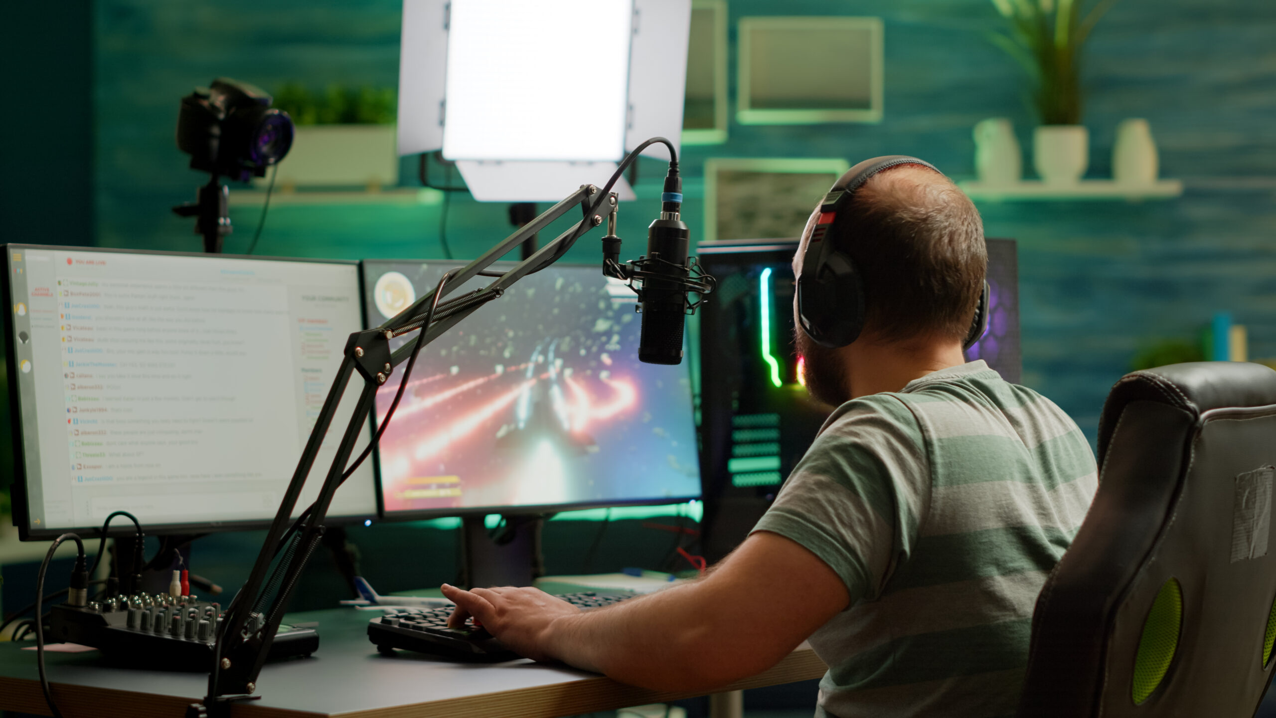 Man streamer playing space shooter videogame using headset, talking on stream chat and microphone. Online streaming cyber performing on RGB powerful professional computer during gaming tournament