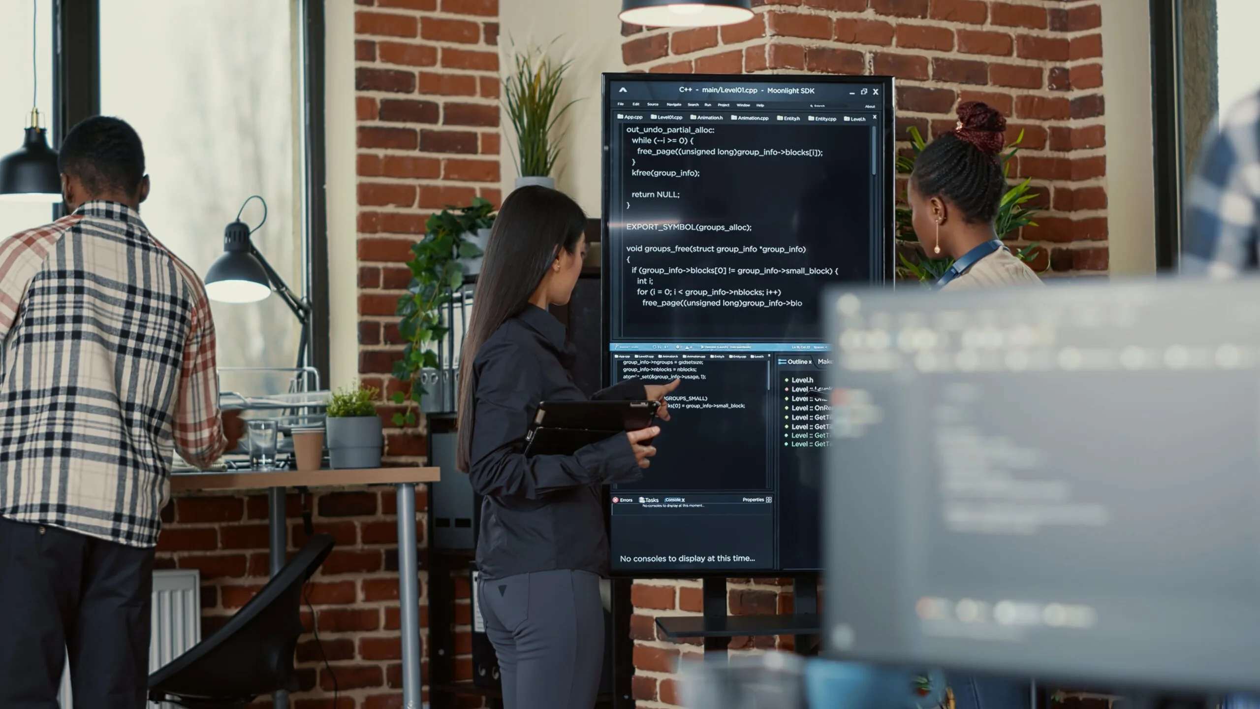software-engineer-holding-digital-tablet-analyzing-code-wall-screen-tv-explaining-errors-colleague