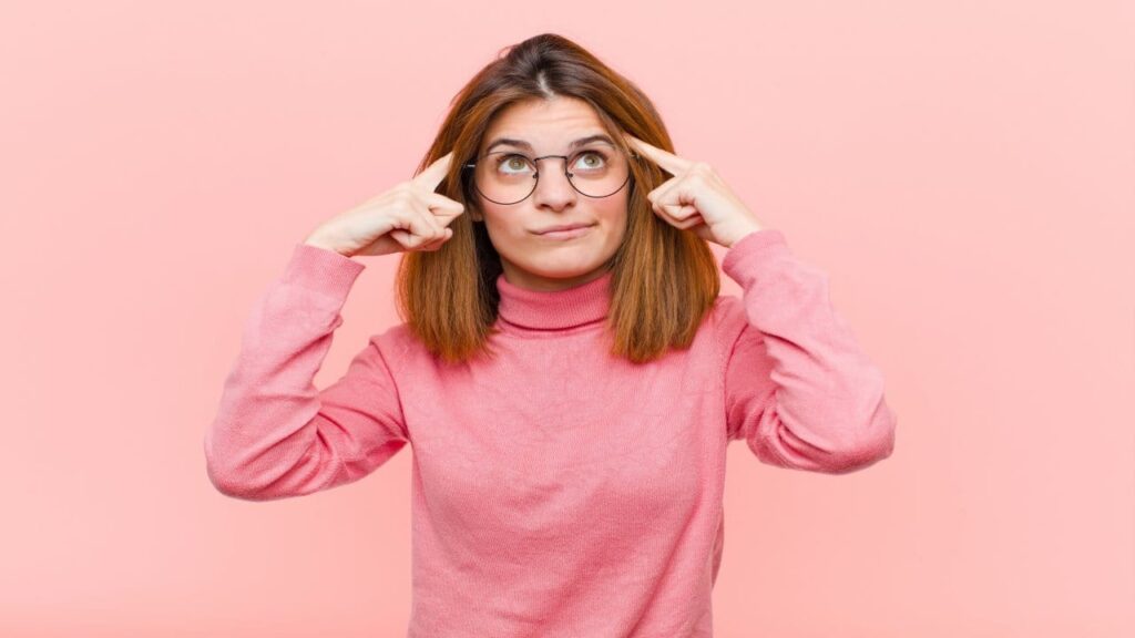 a girl thinking hard on an idea with a pink background