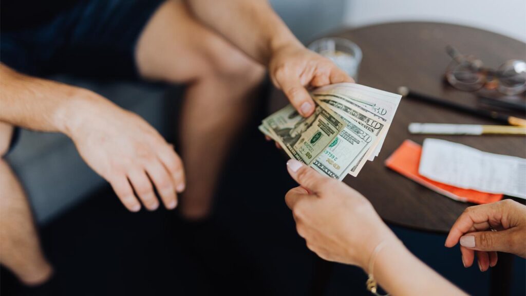 two people trading dollar bills
