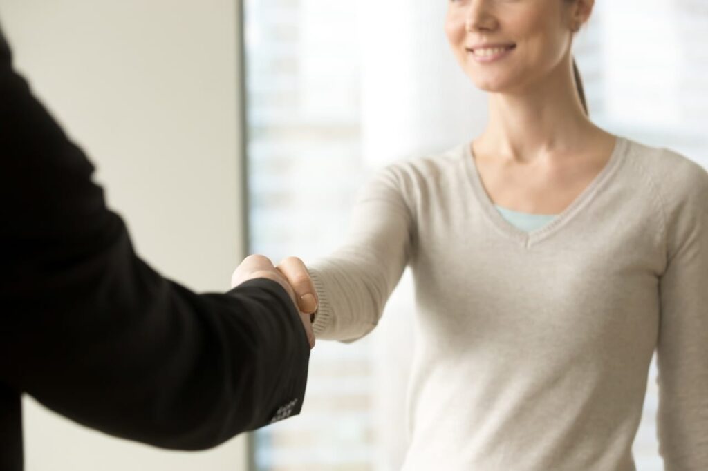 a smiling woman shaking a man's hand