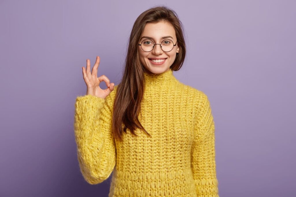 a female in glasses makes okay gesture