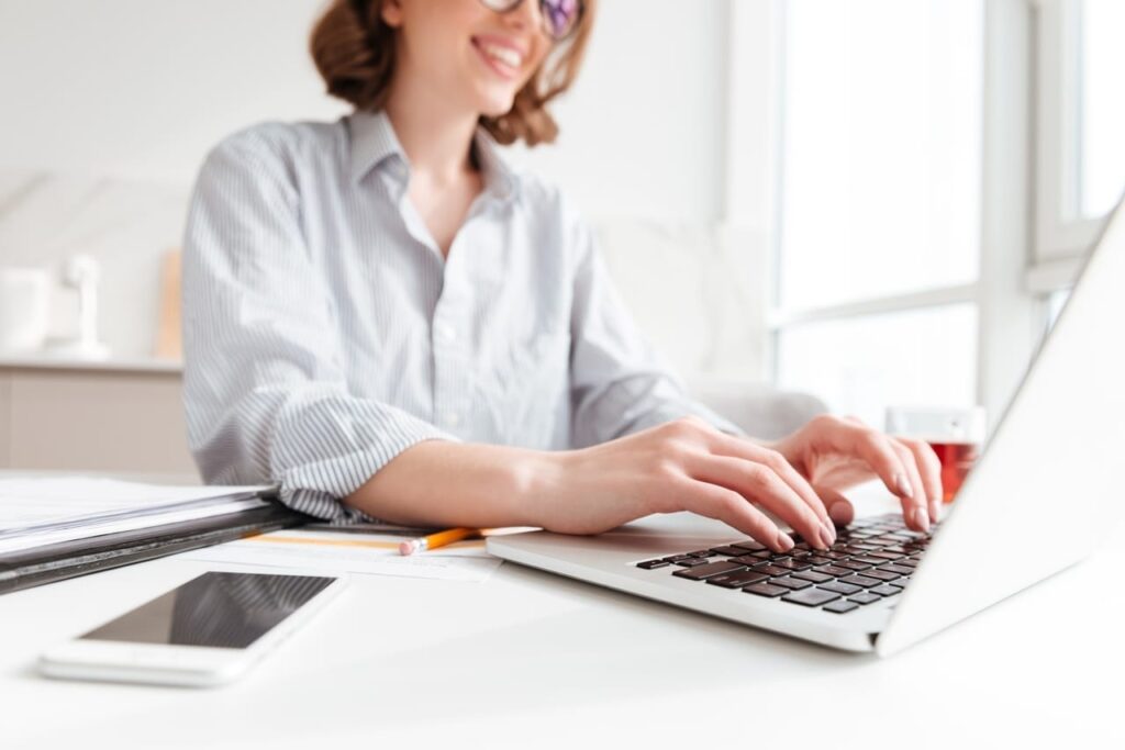 a smiling woman typing something on her laptop