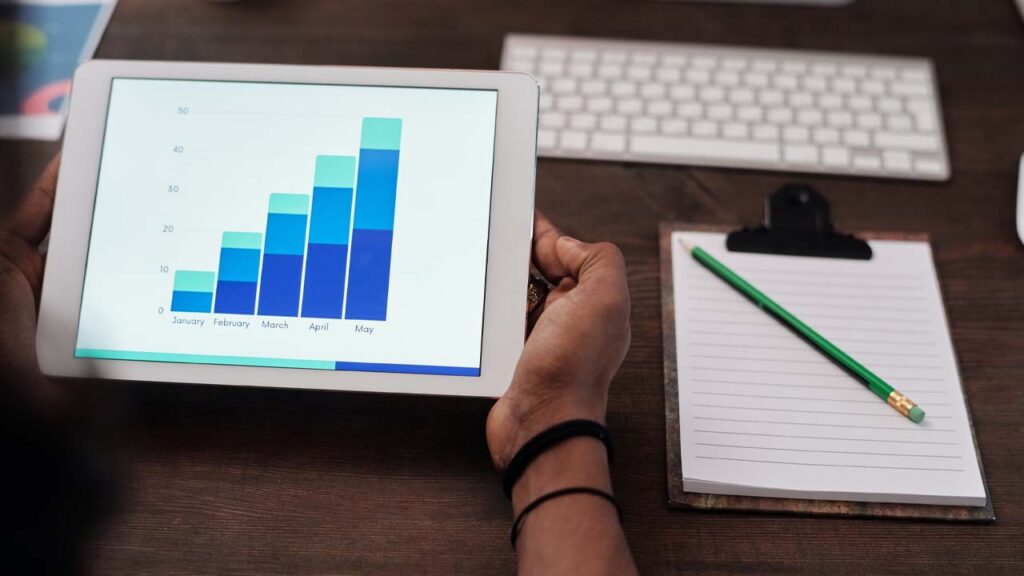 person holding tablet with monthly bar chart increasing