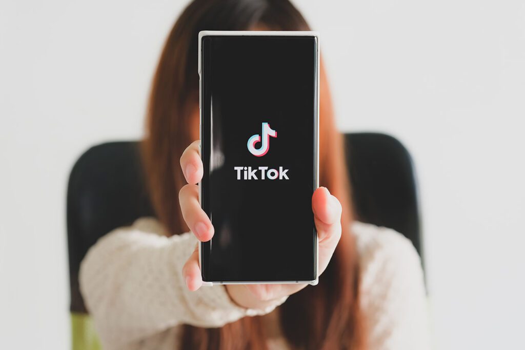 woman holding a phone showing TikTok logo