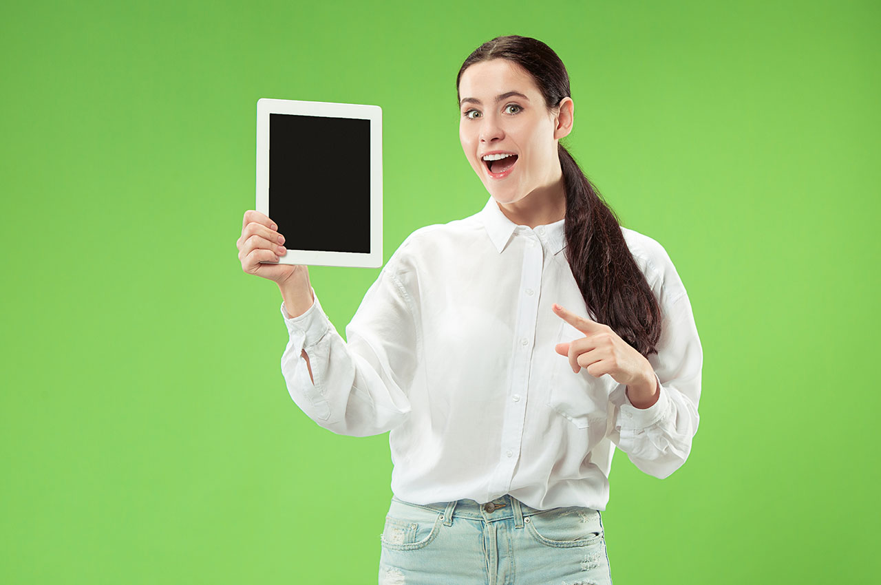 woman standing in front of a green screen holding an ipad tablet