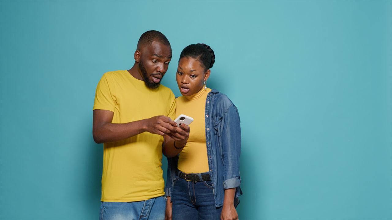 two people stare at a mobile phone