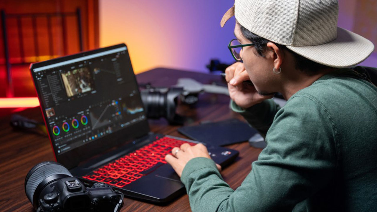 man working on editing project on laptop with camera