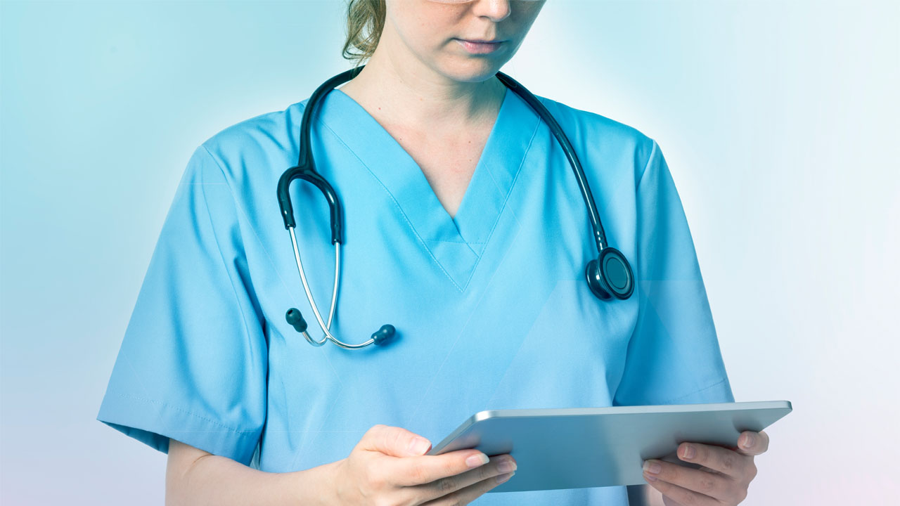 nurse in scrubs looking at a tablet