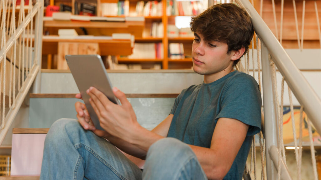 a boy in a library going over elearning content on a tablet