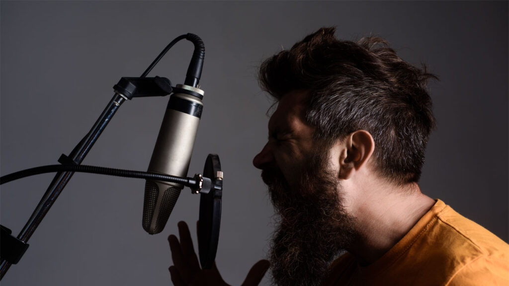 male voice actor screaming at a mic