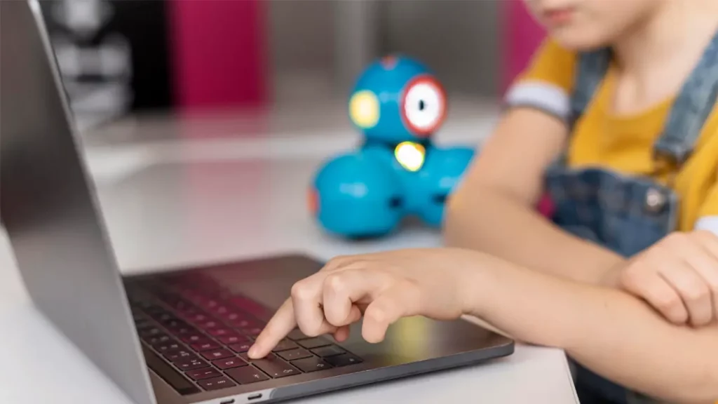 a child pressing a key on their laptop
