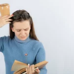 woman with coffee cup squinting at book