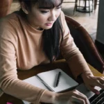 woman with notebook typing on computer