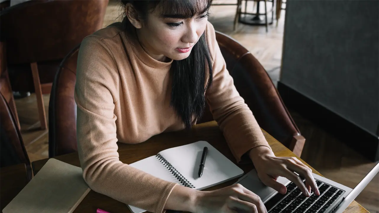 woman with notebook typing on computer