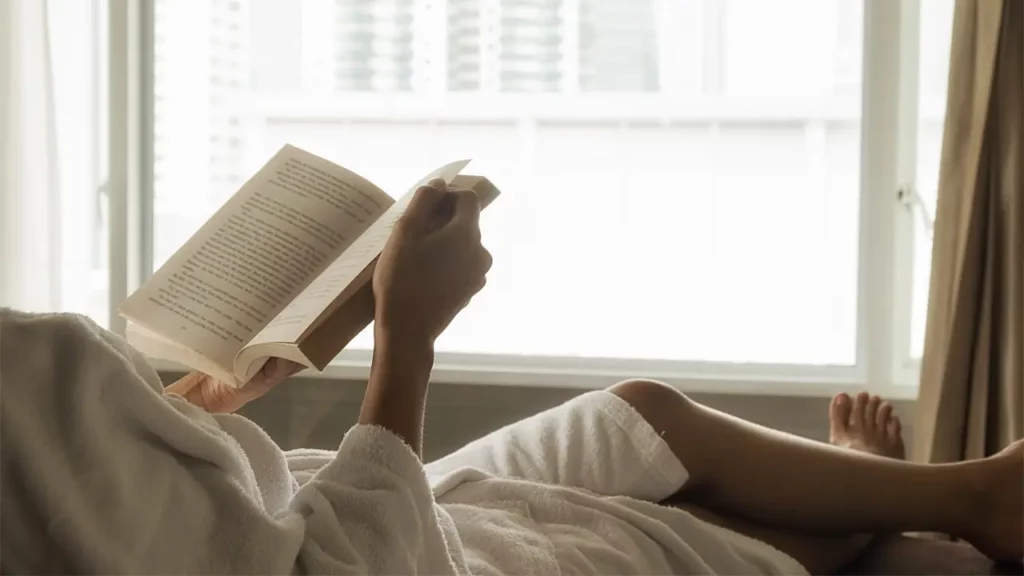 woman in bathrobe reading book