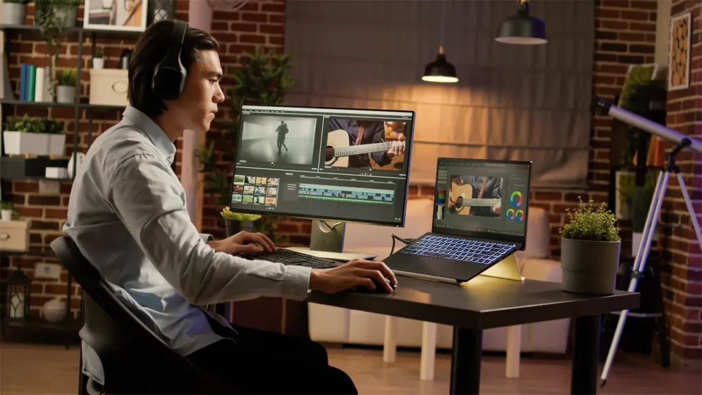 man with headphones on laptop and desktop computer