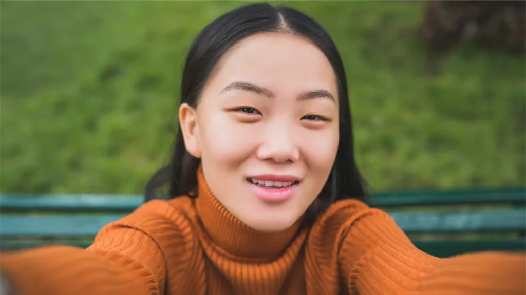 A young woman taking a selfie and smiling.