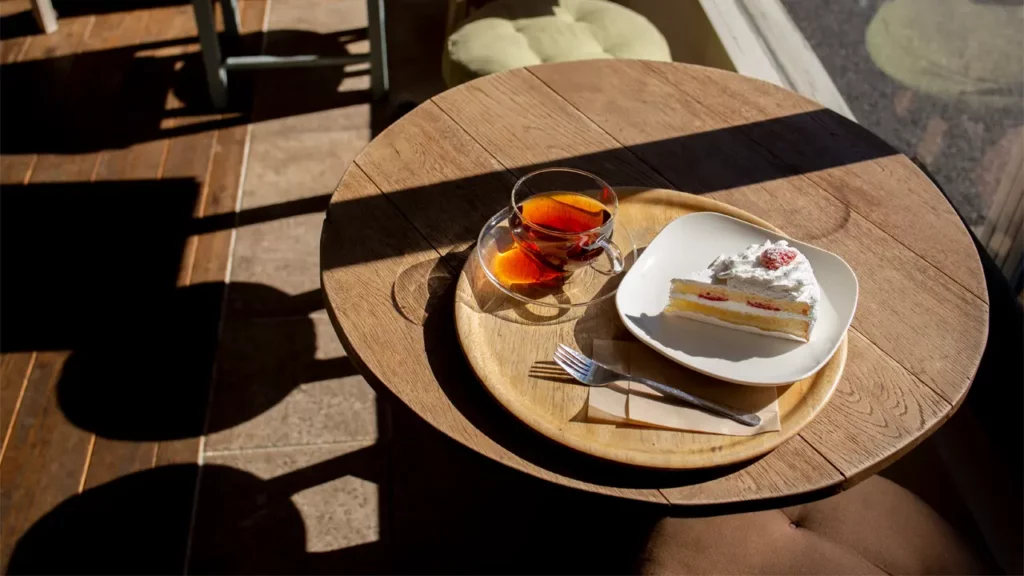 A cup of tea and a cake on a table in a cafe.
