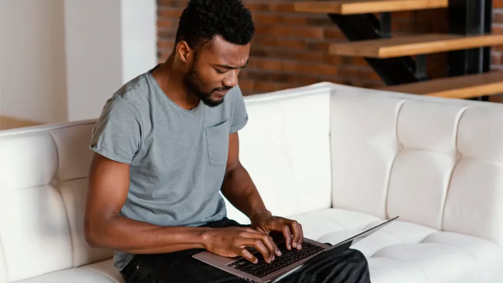 man sitting on couch while typing on his computer