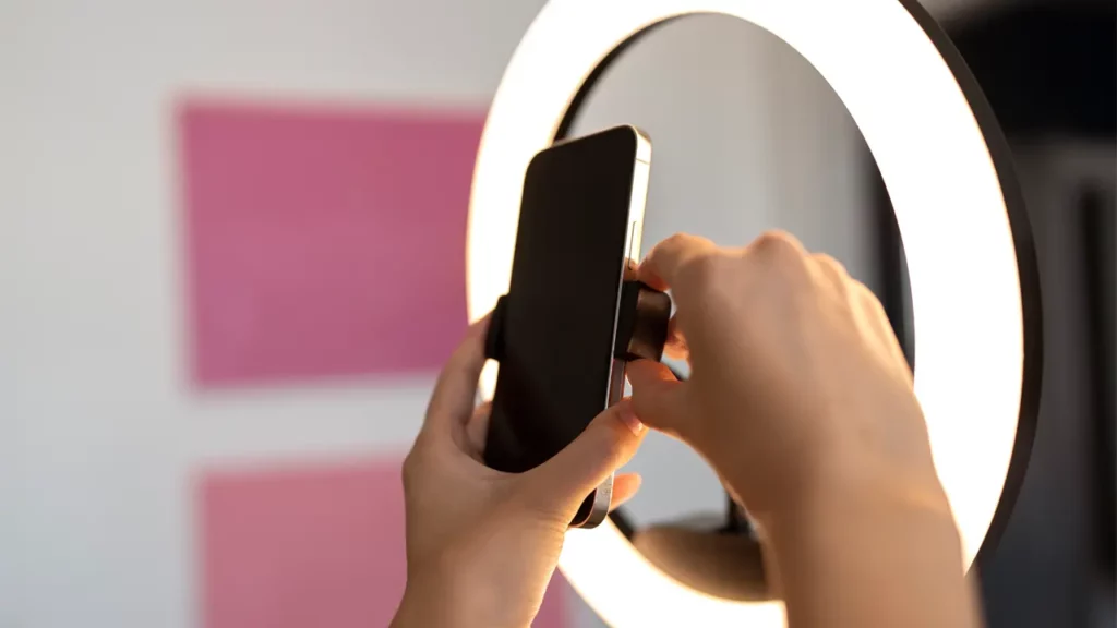 hands adjusting a phone in front of a ring light