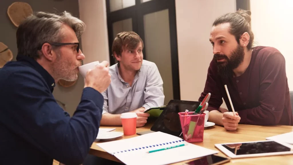 Three people talking at the desk.