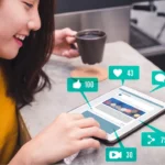 Person using a tablet with social media engagement icons.