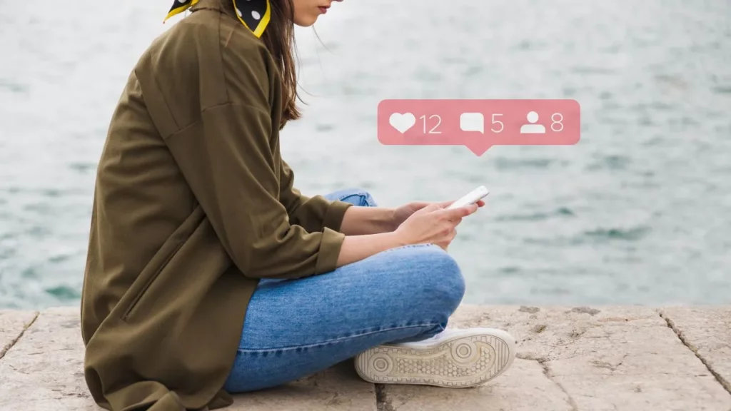 Person using a phone by the sea.
