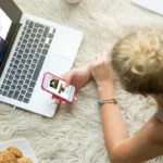 Woman using laptop and phone on a cozy rug.
