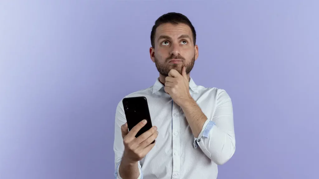A man thinking while holding his smart phone.
