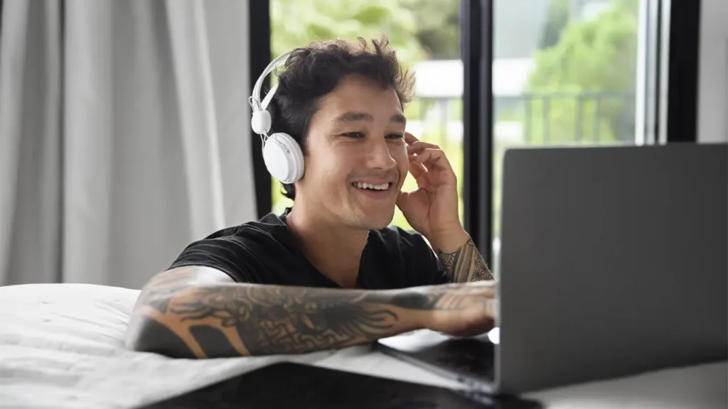 A man listening to audio on his laptop.