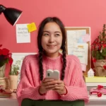 A young woman smiling with a phone.