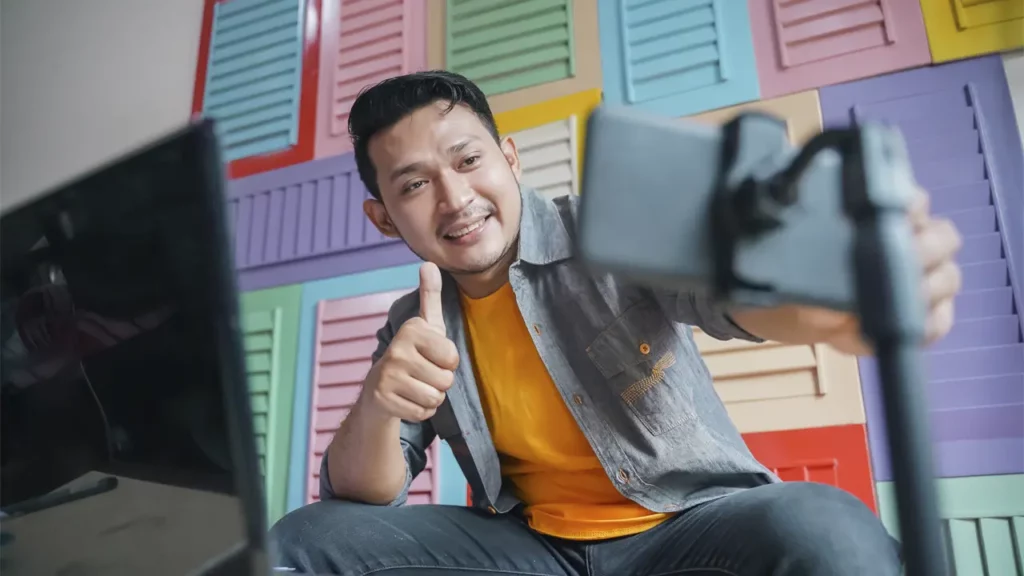 A man creating video content using his phone and computer.
