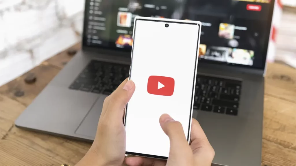 A person using YouTube on both their phone and laptop.