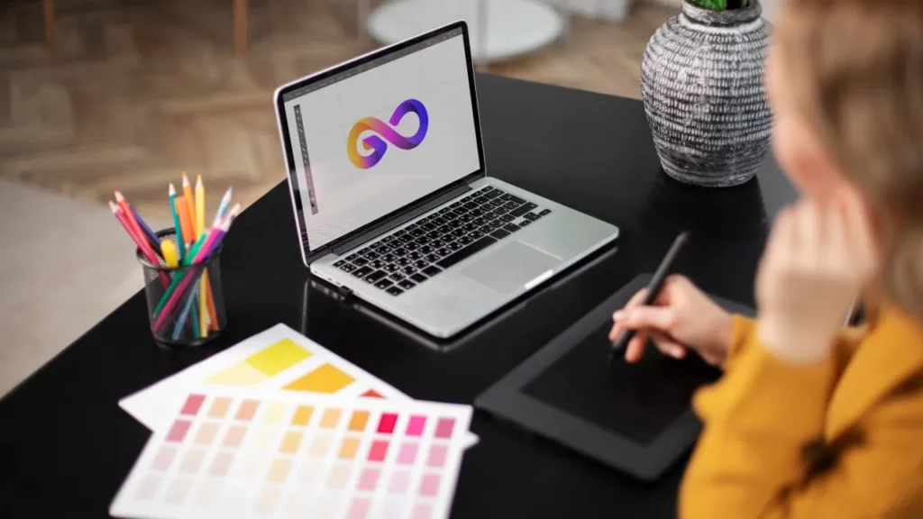 A person at a desk using a laptop and a drawing tablet to work on a graphic design project, showing the creative process.