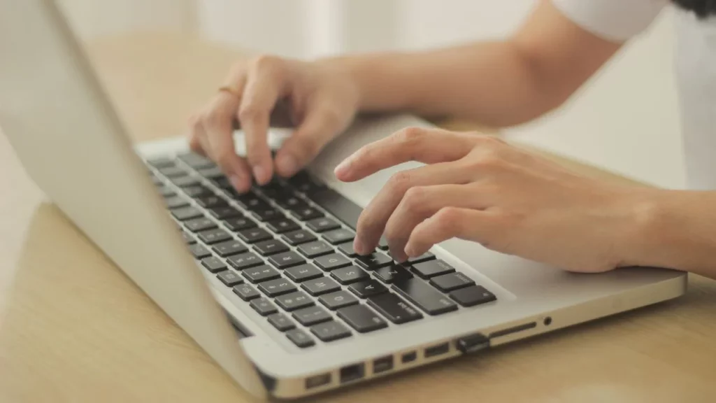 Person typing on a laptop keyboard with hands close-up.