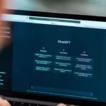 Person using a laptop to access ChatGPT website with examples, capabilities, and limitations displayed.