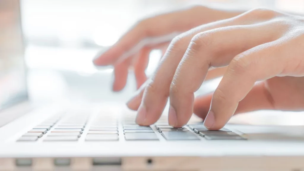 Hands typing on a laptop keyboard.
