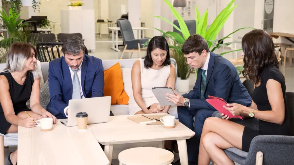 A team of professionals discussing around a table with laptops and charts.