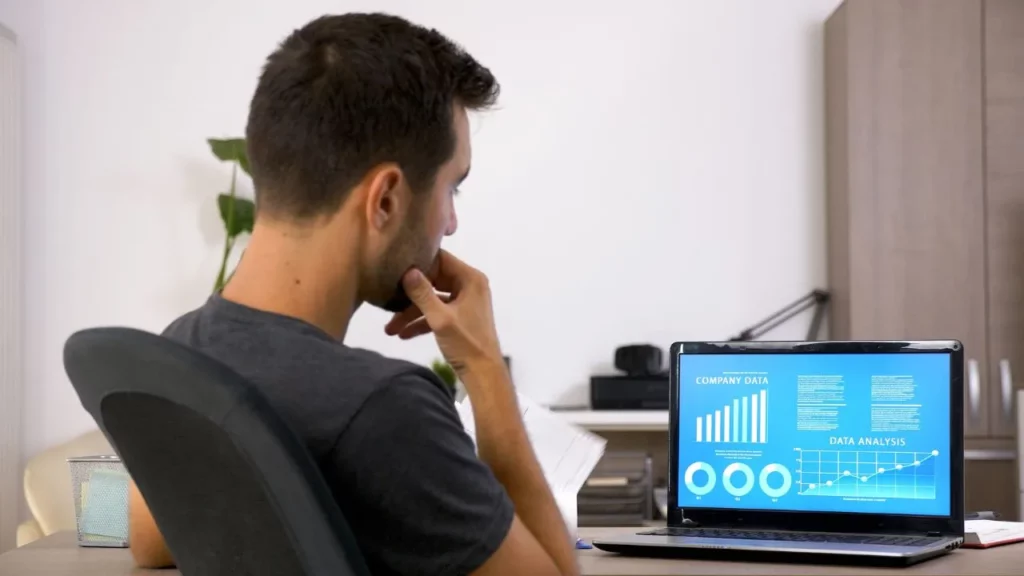 A person analyzing charts and data on a laptop screen.