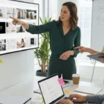 A group of people collaborating in a meeting, pointing at a large screen with design images.
