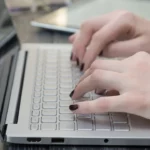 Hands typing on a laptop keyboard.