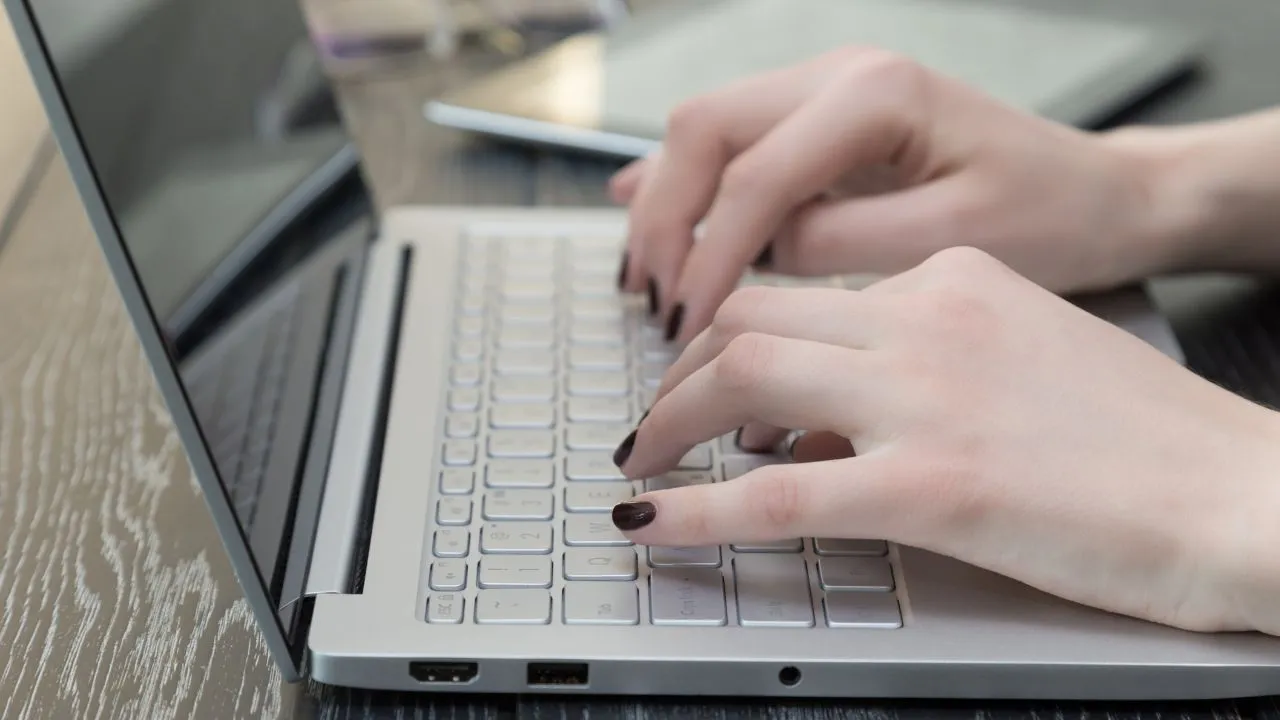 Hands typing on a laptop keyboard.