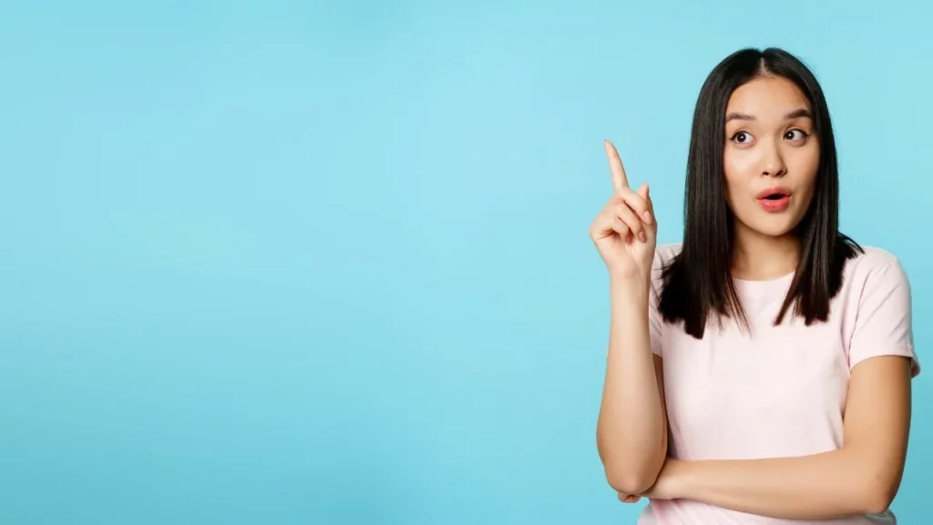 Woman with an idea, pointing finger up against a blue background.