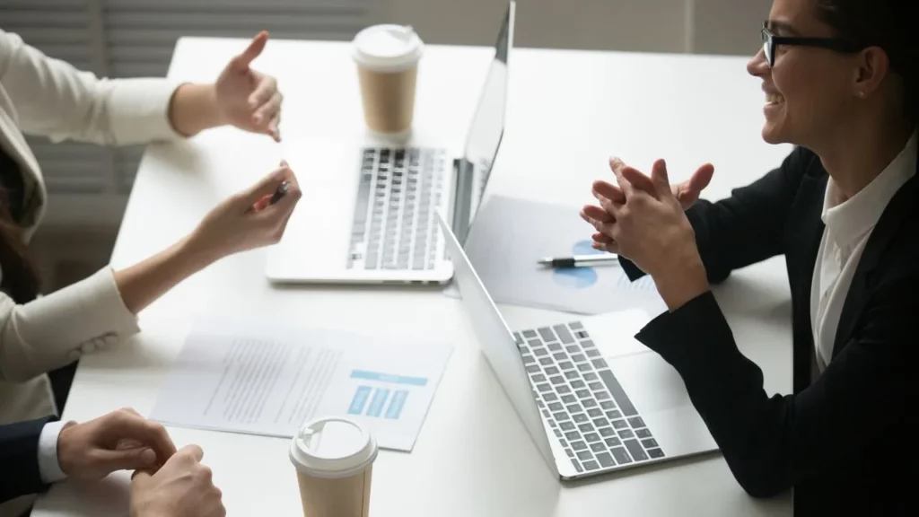 Business meeting with people discussing around laptops and coffee cups.