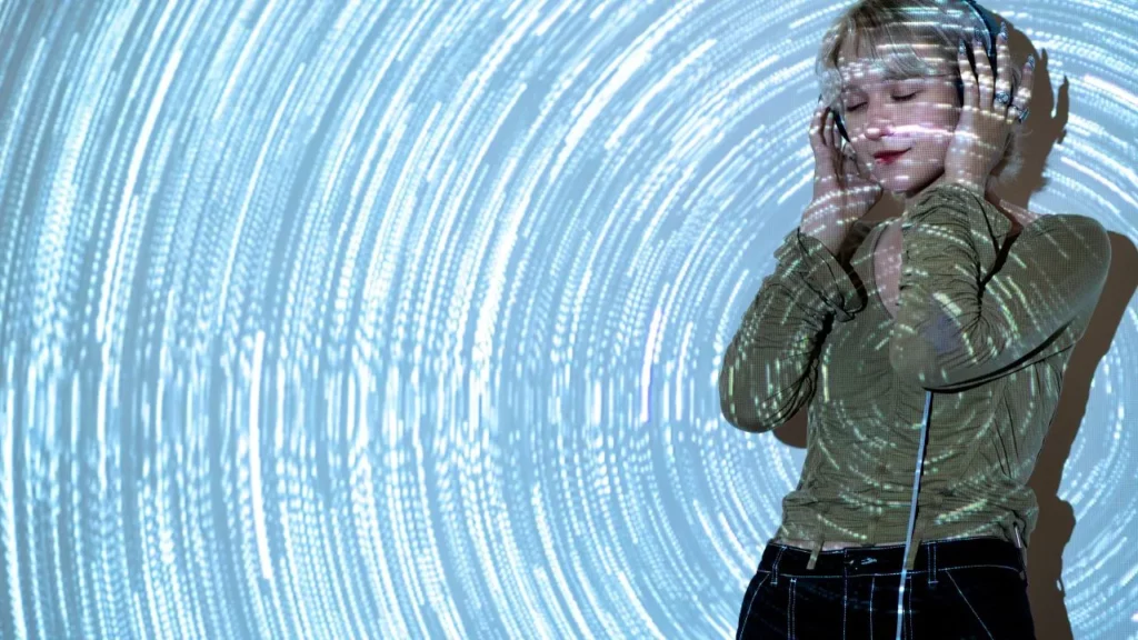 Woman listening to headphones with abstract light patterns in the background.