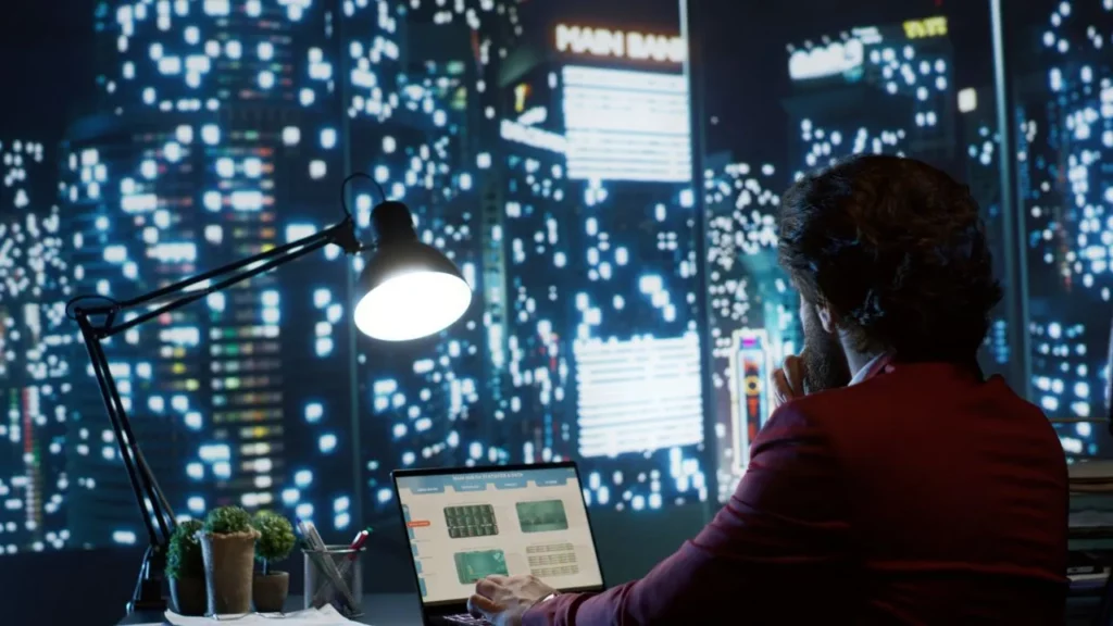 Person working on a laptop with a cityscape backdrop at night.