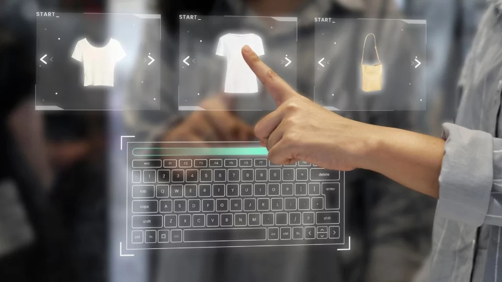 Hand interacting with a holographic interface showing clothing items like a white t-shirt and a beige handbag above a projected keyboard.