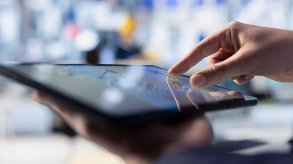 A person taps on a tablet screen while shopping online, with a blurred background.